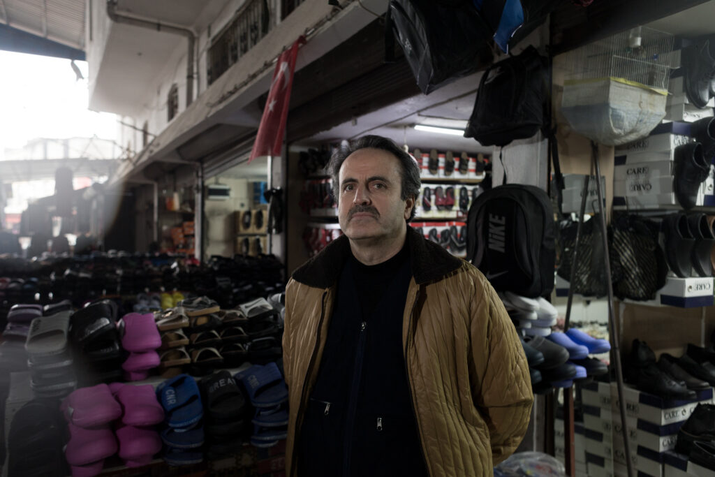 Adam Sabit stands next to his stall in an Antakya Bazaar (Kyriakos Finas)