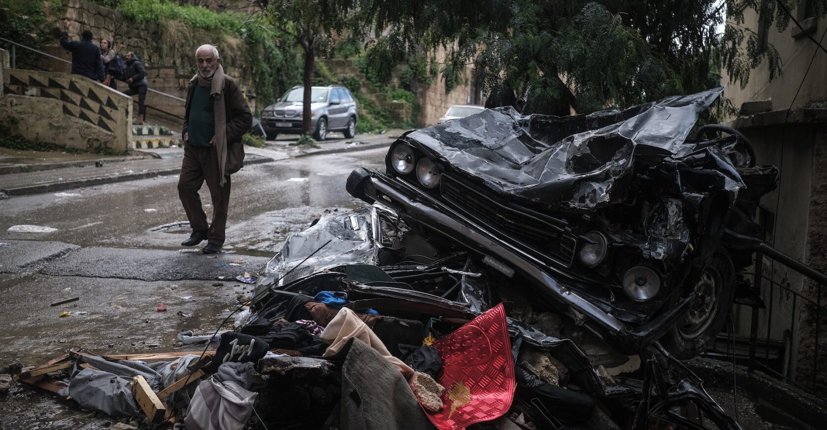 A man walks past crushed cars in the wake of a building collapse in Tripoli (João Sousa)