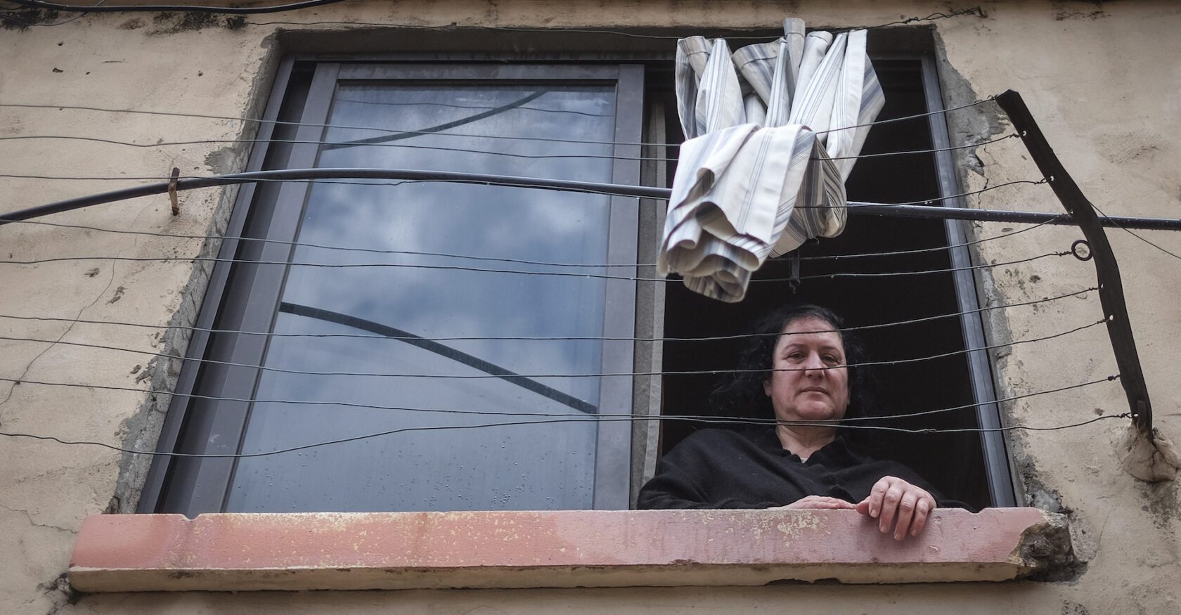 Samar Dinnawi, who lives across the alleyway from a recently collapsed building, looks from her window (João Sousa)