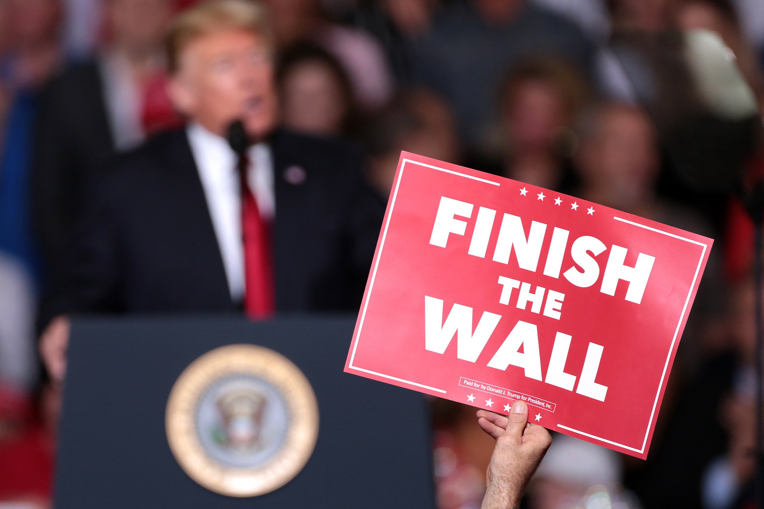 An attendee holds a sign that says 'finish the wall' at a Trump rally in Mesa, Arizona, on Oct. 19, 2018 (Gage Skidmore/Wikimedia Commons)