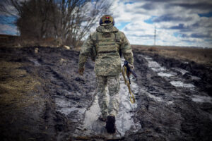 A Ukrainian military officer walks along a muddy road toward trench lines in northern Ukraine in March.