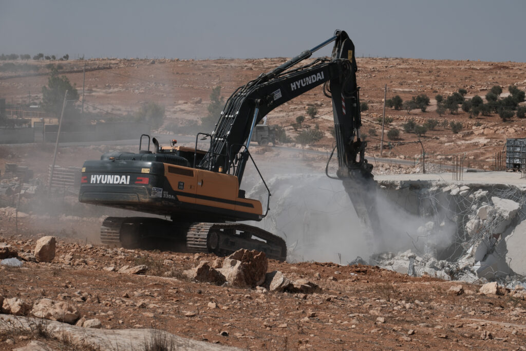 A bulldozer tears through the concrete roof of the single-story home where Osama planned to marry (Andrew Waller/Inkstick)