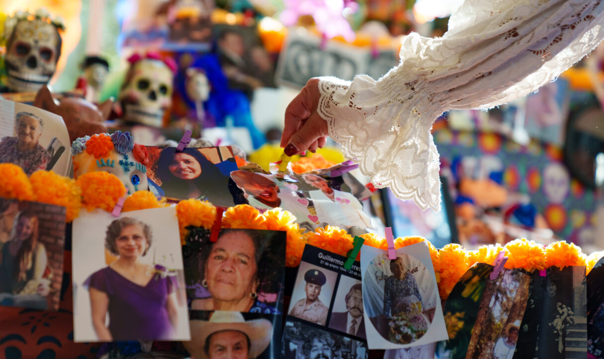 A guest places a photo of a loved one at the White House’s ofrenda to mark Día de los Muertos, Thursday, October 31, 2024, on the East Landing. (Official White House Photo by Abe McNatt)