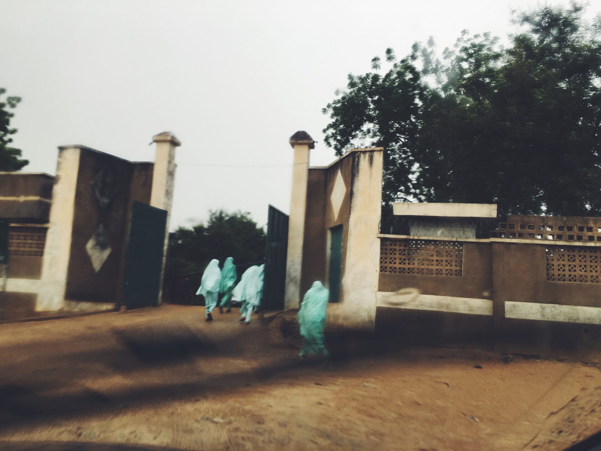 young girls in hijabs run through a gate in Nigeria