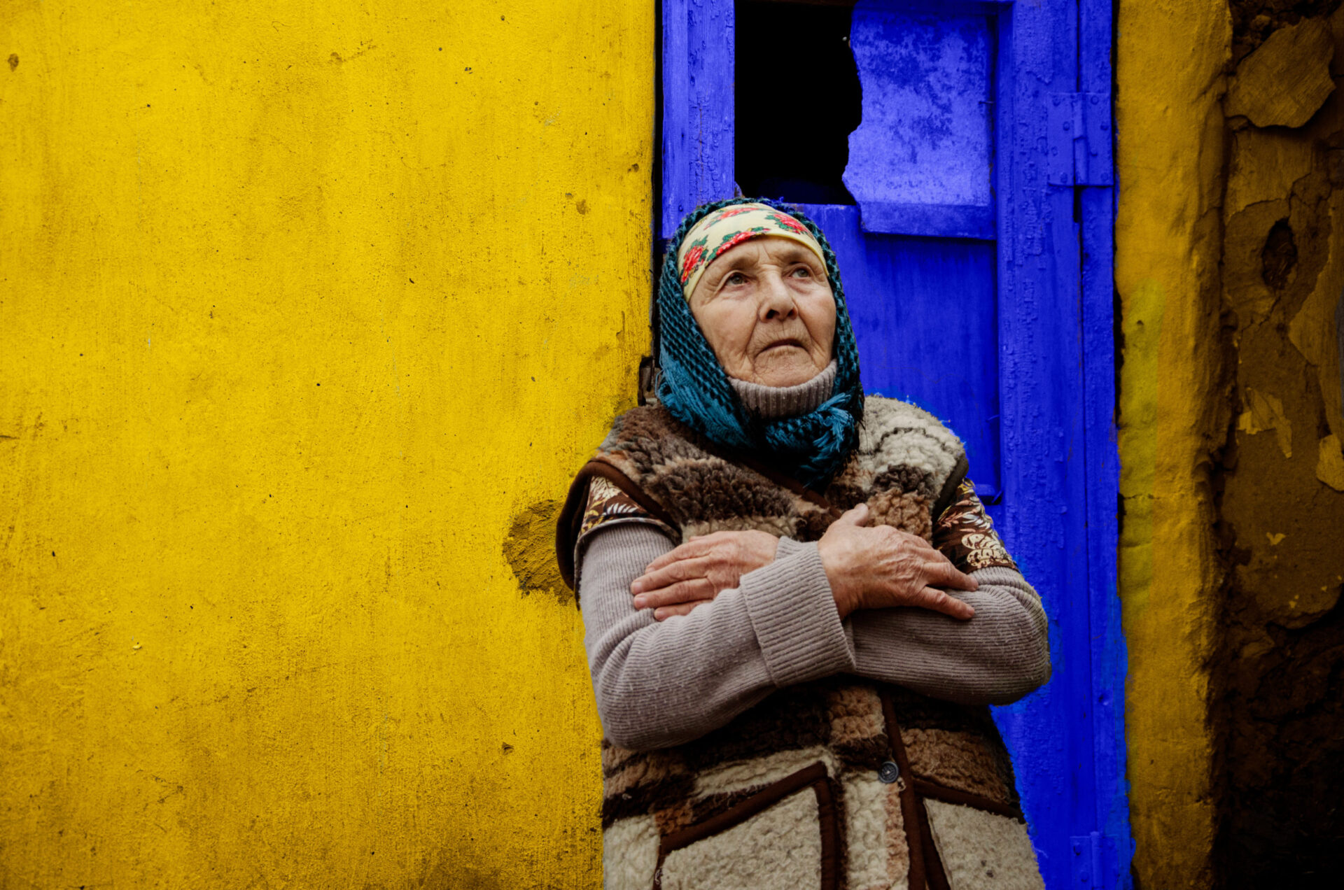 An old grandmother in the background of a yellow slum. Poor area