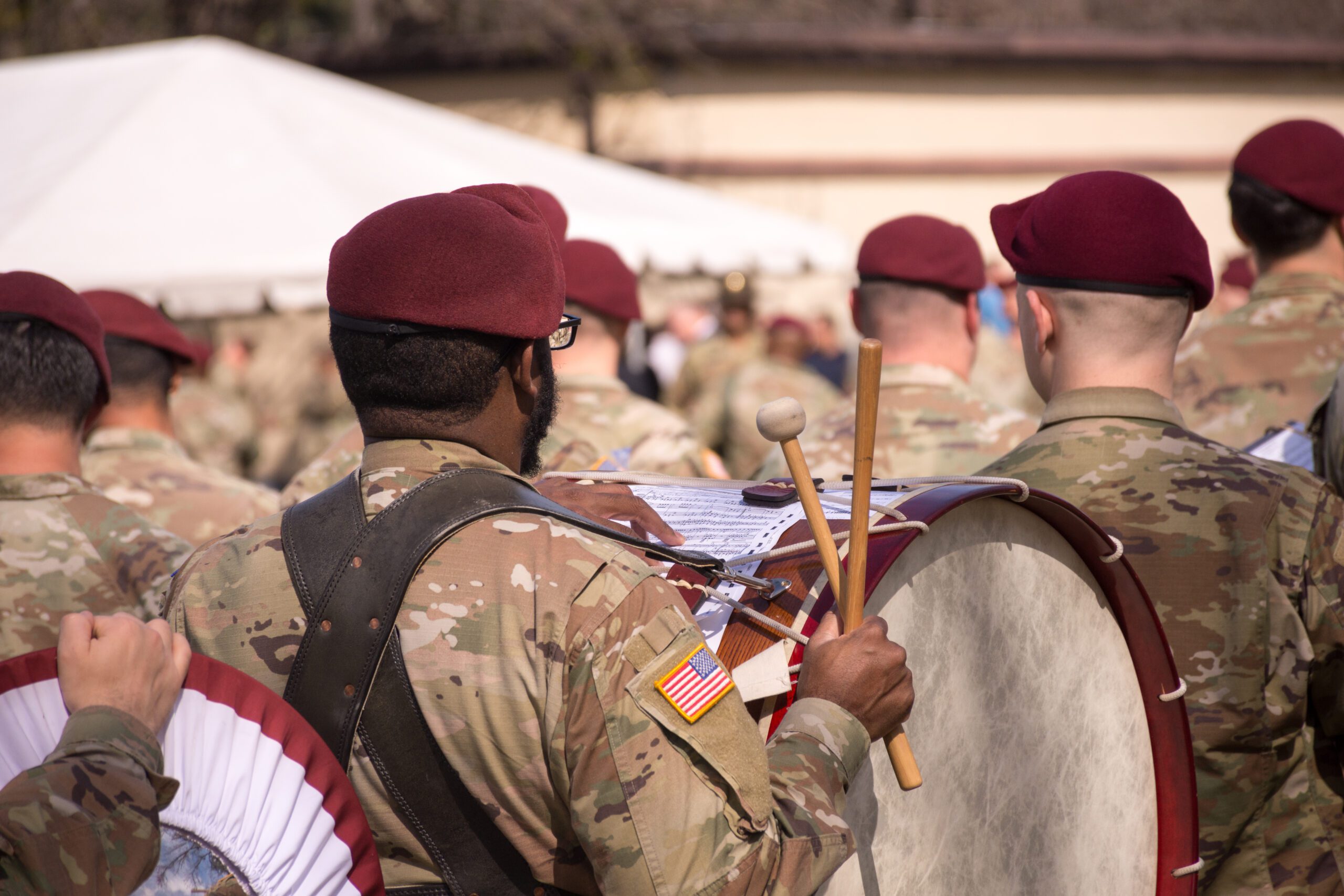 82nd Airborne Ceremonial Band on Stang Field, Fort Bragg, North Carolina. Close-up of bass drummer carrying drum, sticks at the ready to perform, with other musicians.