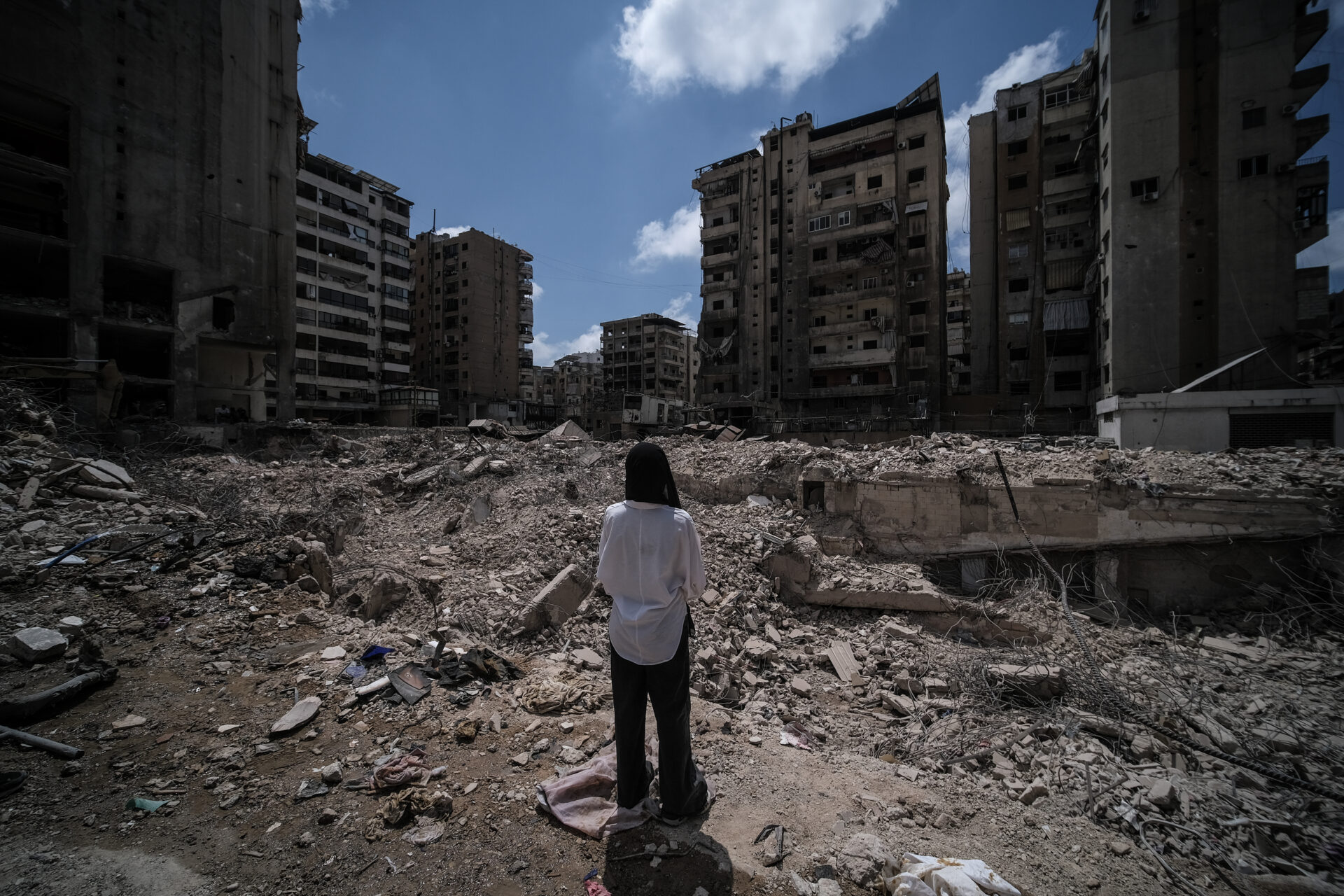 A woman in the Beirut suburbs studies destruction caused by an Israeli strike (João Sousa)