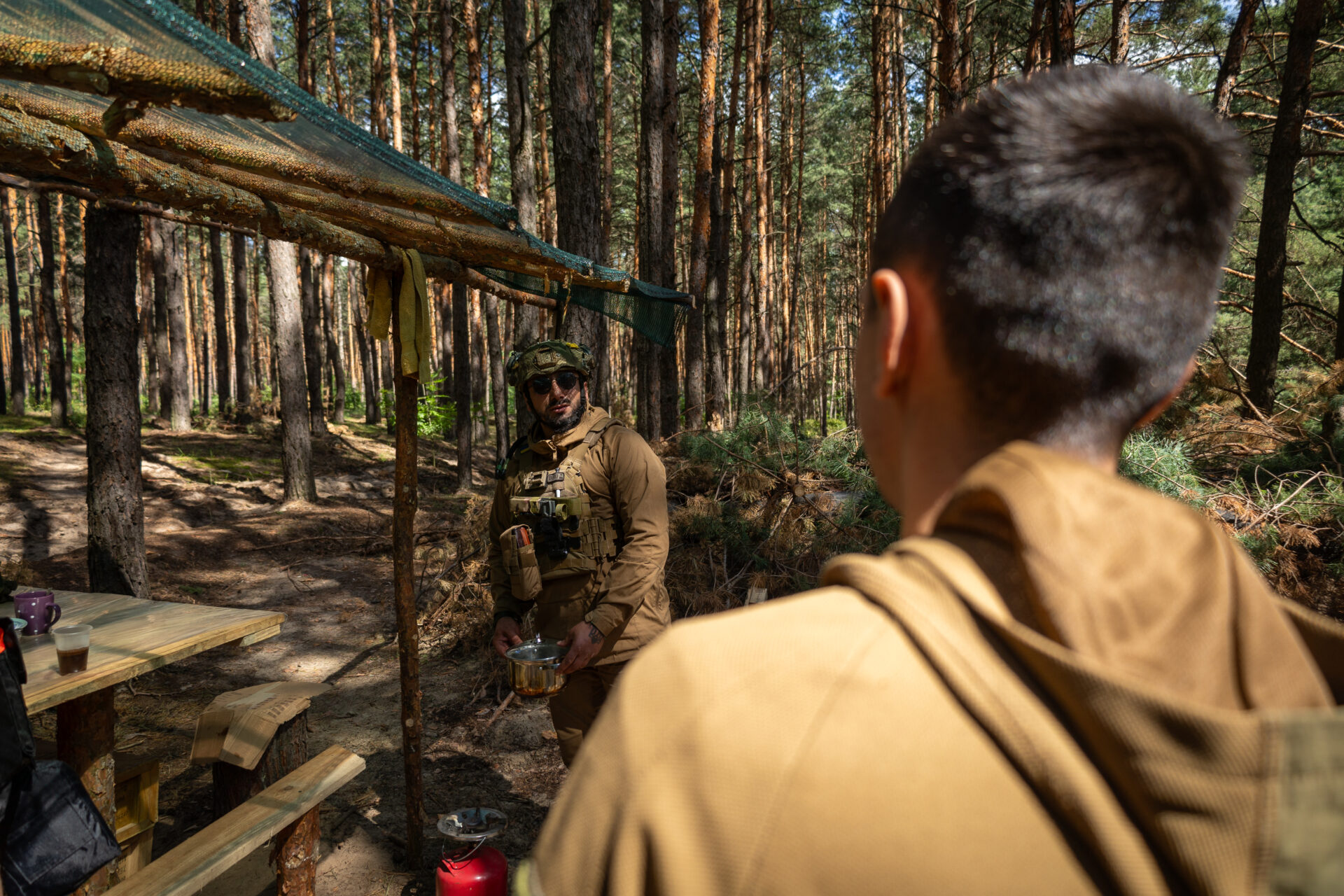 Captain Shustriy, a company commander in Ukraine’s 14th Separate Mechanized Brigade, speaks with Czech, a combat medic, at a position along the frontlines in northeast Ukraine in mid-July.