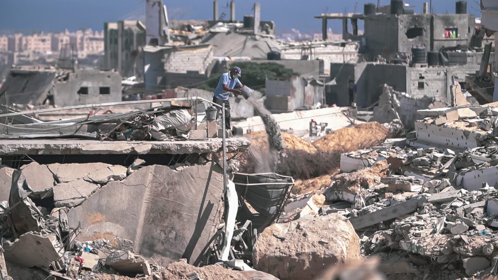 A photo published in February 2025 shows a man removing rubble amid destruction in Gaza (Jaber Jehad Badwan/Wikimedia Commons)