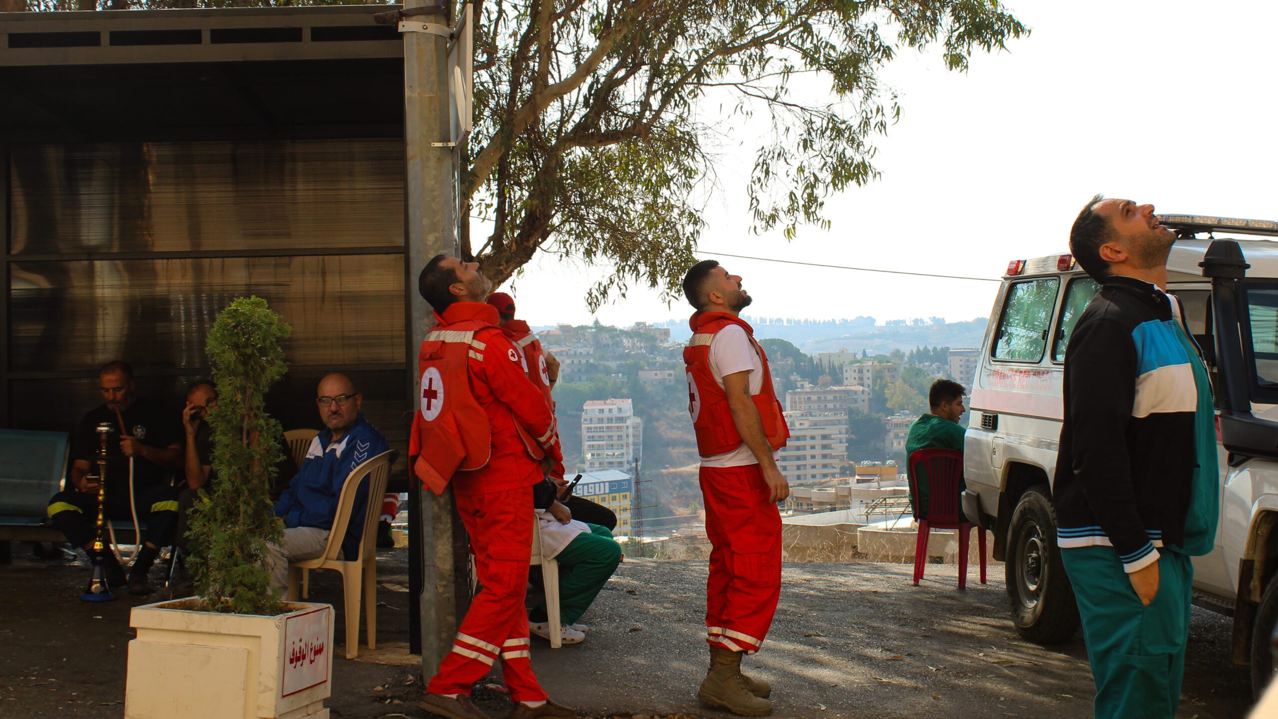 A group of rescue volunteers in Lebanon look at an Israeli drone buzzing overheard (Hanna Davis)