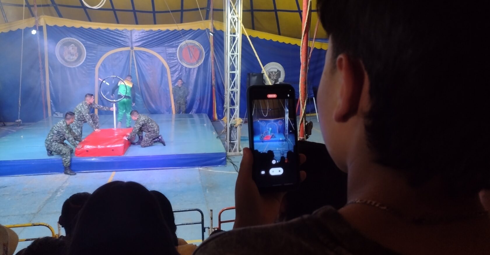 Soldiers prepare the next circus act as a young audience member films in Supatá, Colombia, on Wednesday, April 8, 2026. (Natalie Skowlund, Inkstick Media)