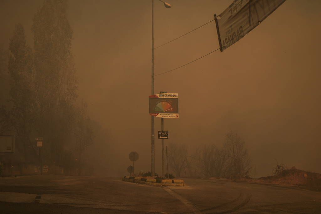 In Varnavas, smoke surrounds a sign that informs residents of the fire alert level (Nick Paleologos)