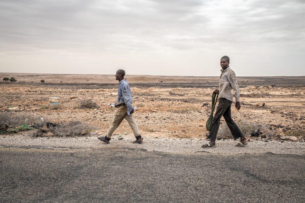 Two men making the migration journey walk along the road en route to Bosaso (Marco Simoncelli)