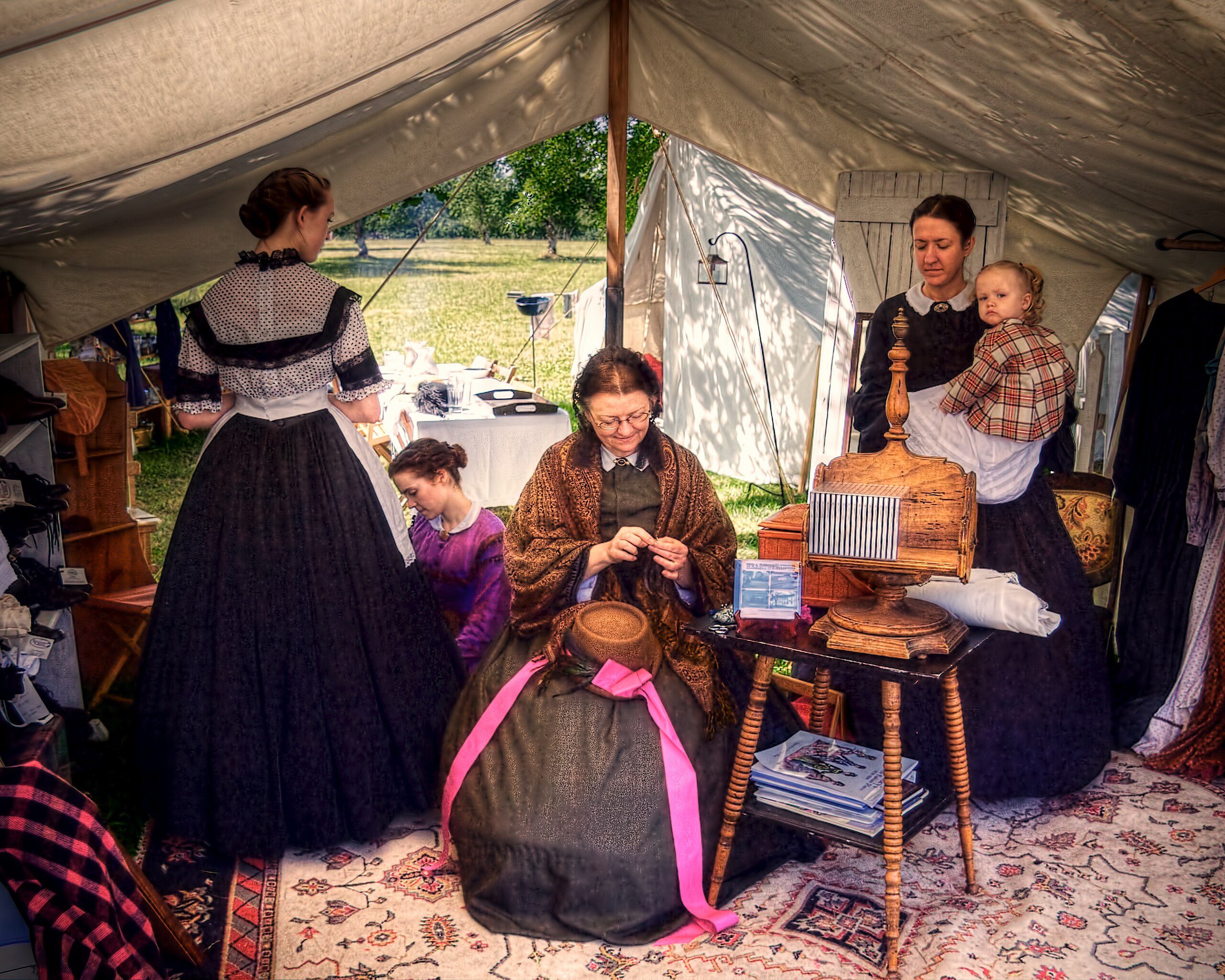 Reenactors_make_dresses_while_one_holds_a_child