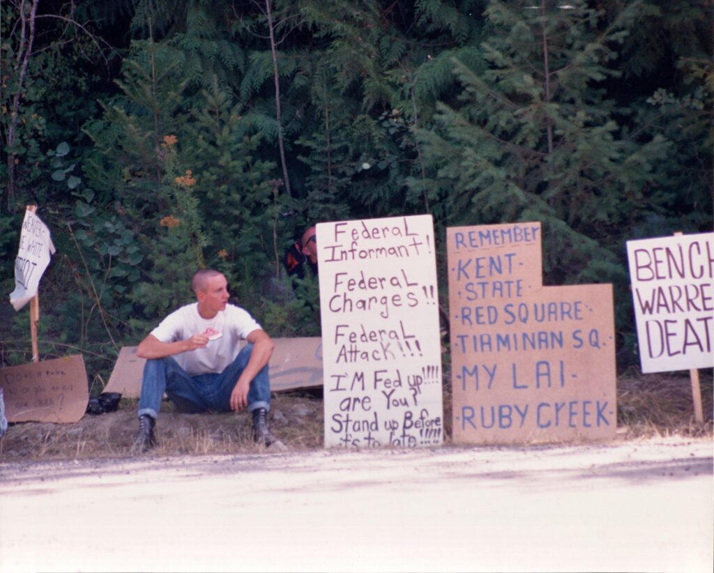 A skinhead sits near signs during protests against the siege at Ruby Ridge in 1992 (Dave Hunt/Wikimedia Commons)