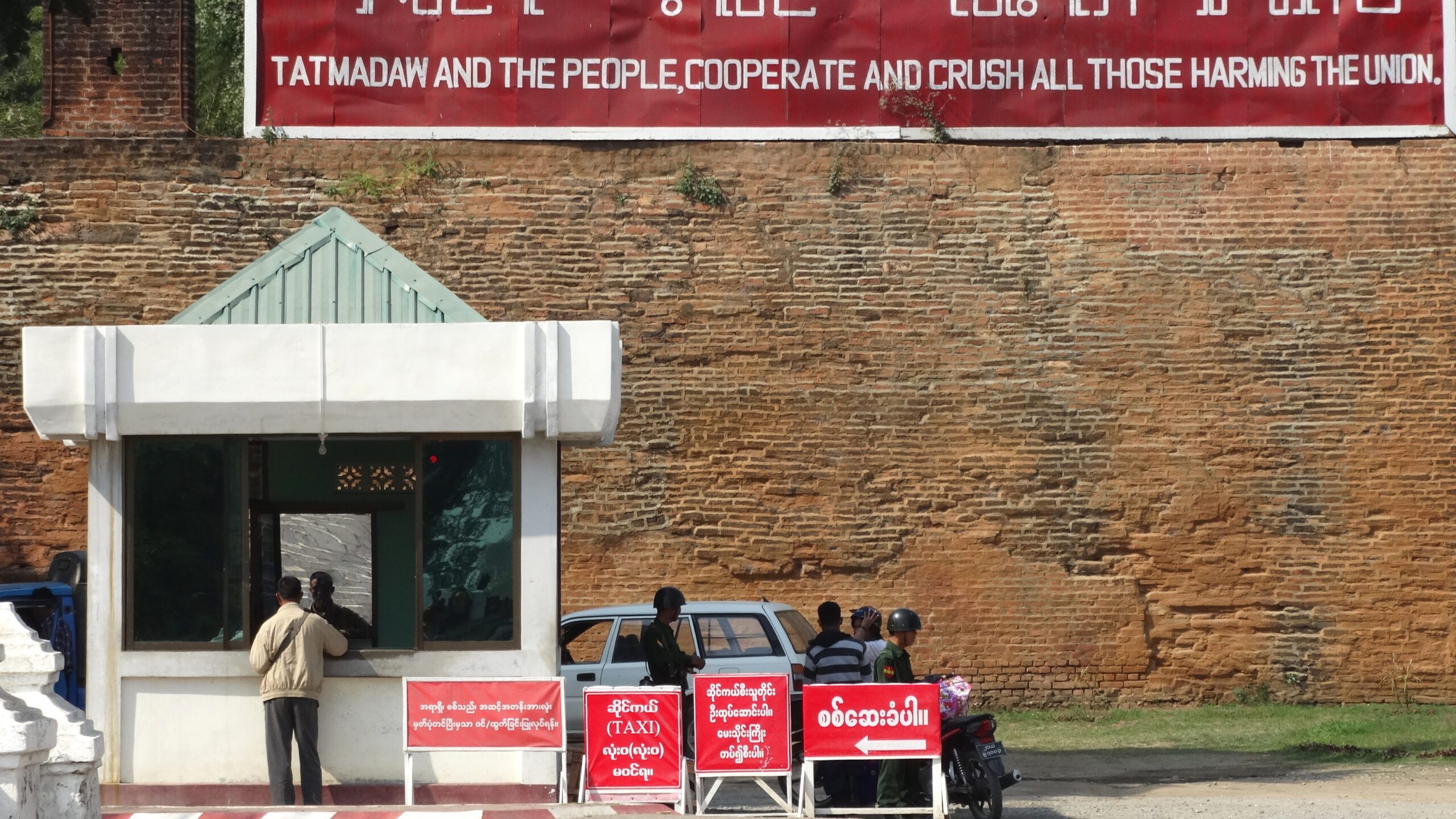 Photographed in 2014, a checkpoint and a banner outside Mandalay Palace (Adams Jones via Wikimedia Commons)