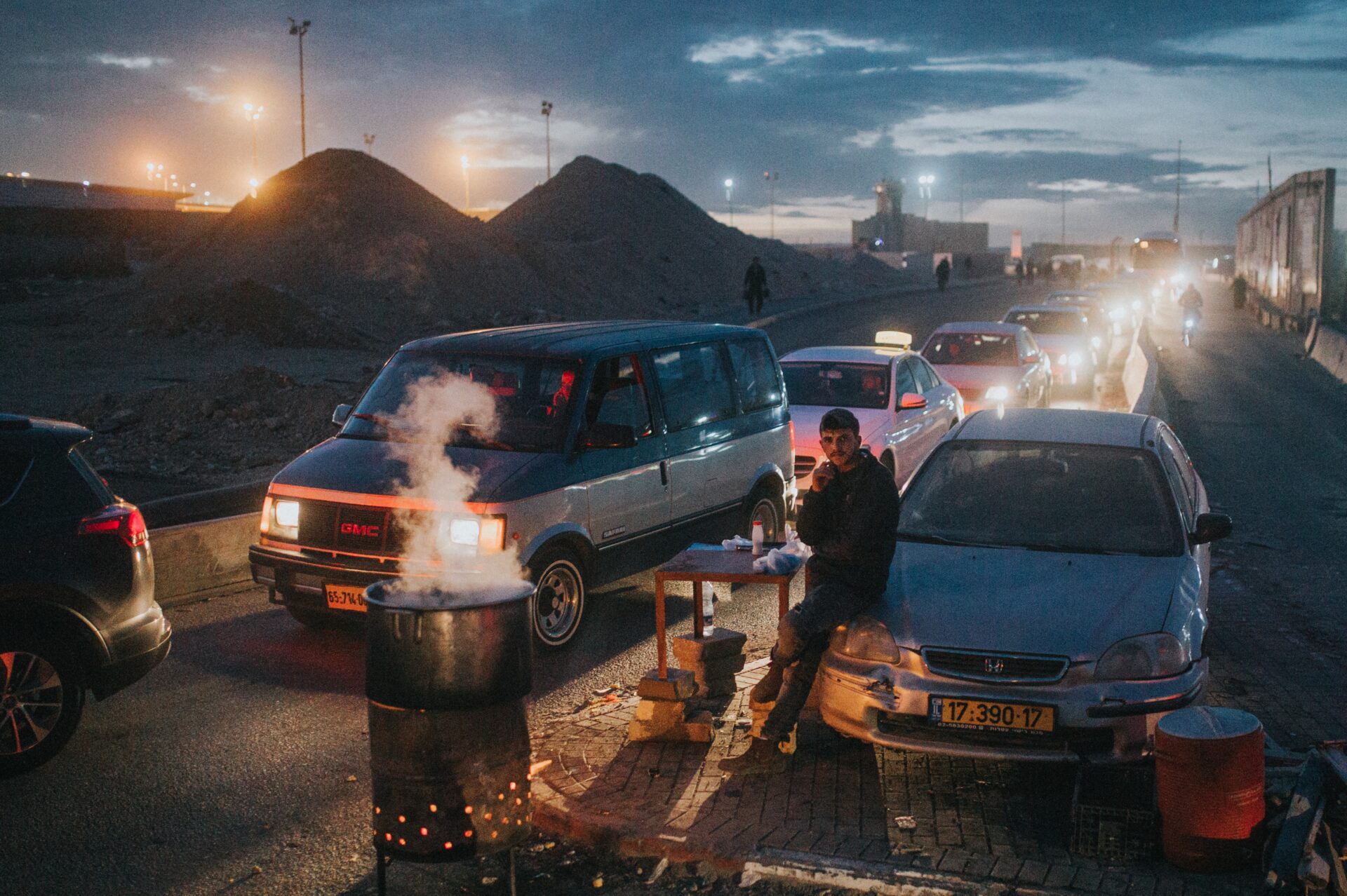 A man waiting by lines of cars going through a checkpoint from Ramallah, Palestine to enter Israel. Published on Unsplash on Nov. 15, 2018 (Cole Keister)