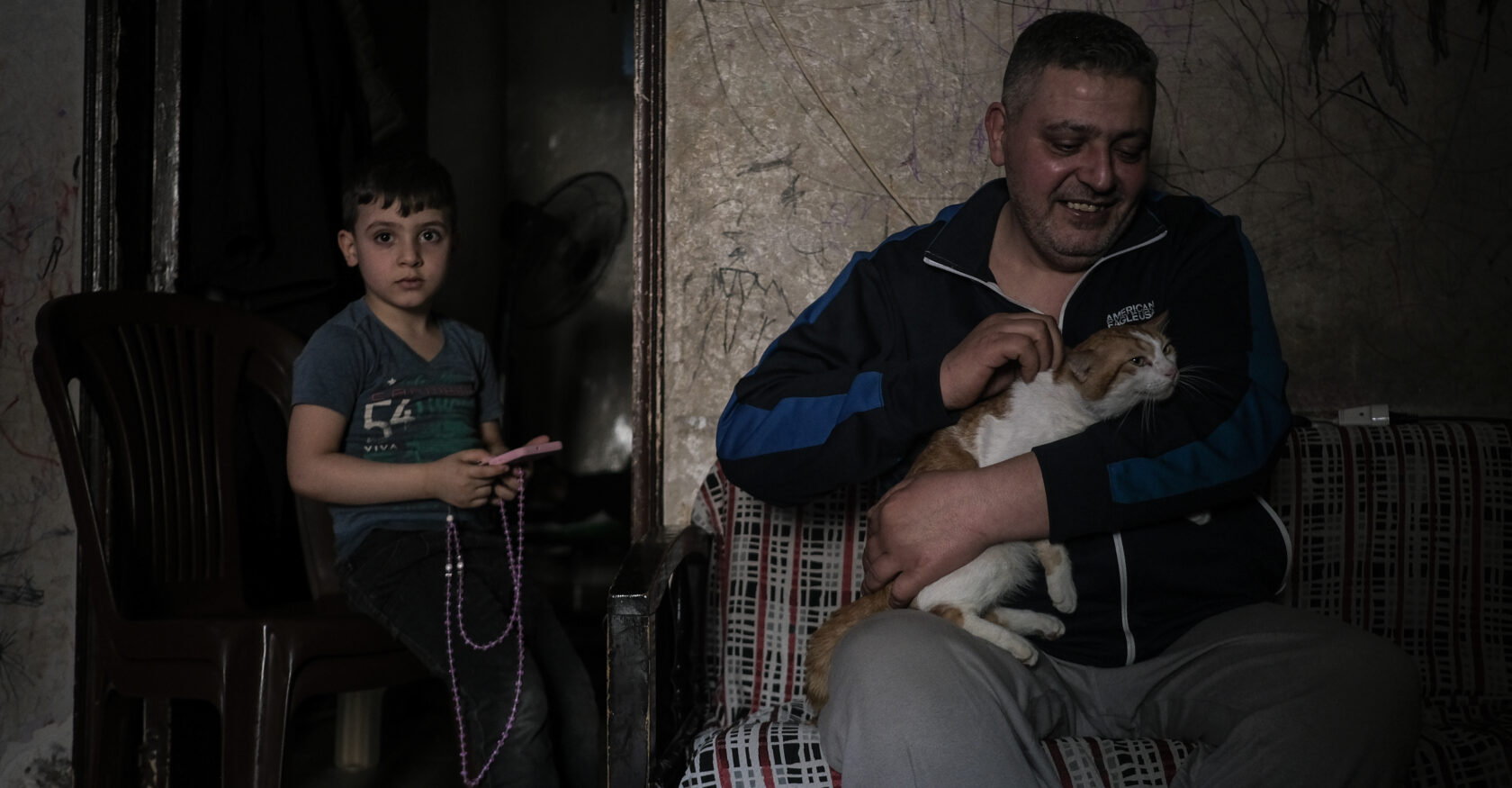 Gaza Hospital resident Ali Hleihel cuddles with the family cat in his family’s makeshift living room on April 8, 2024 (João Sousa)