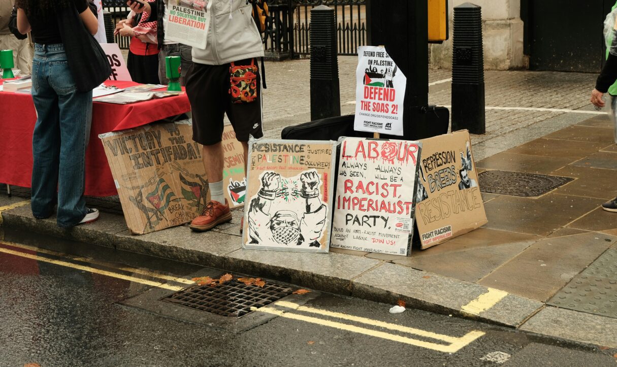 Demonstrators' signs in Westminister, London, photographed in July 2025 (Harrisun S/Unsplash)