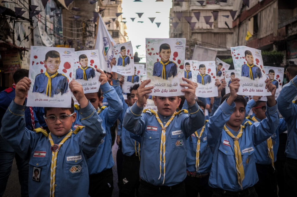 Scouts hold signs with the photo of Bilal Kanj, 11 years old, during his funeral in Ghobeiry, a southern Beirut suburb, on Sept. 18, 2024. Kanj was killed the previous day in an Israeli attack that detonated Hezbollah members’ pagers. His funeral was later interrupted by further explosions of communications devices (João Sousa)