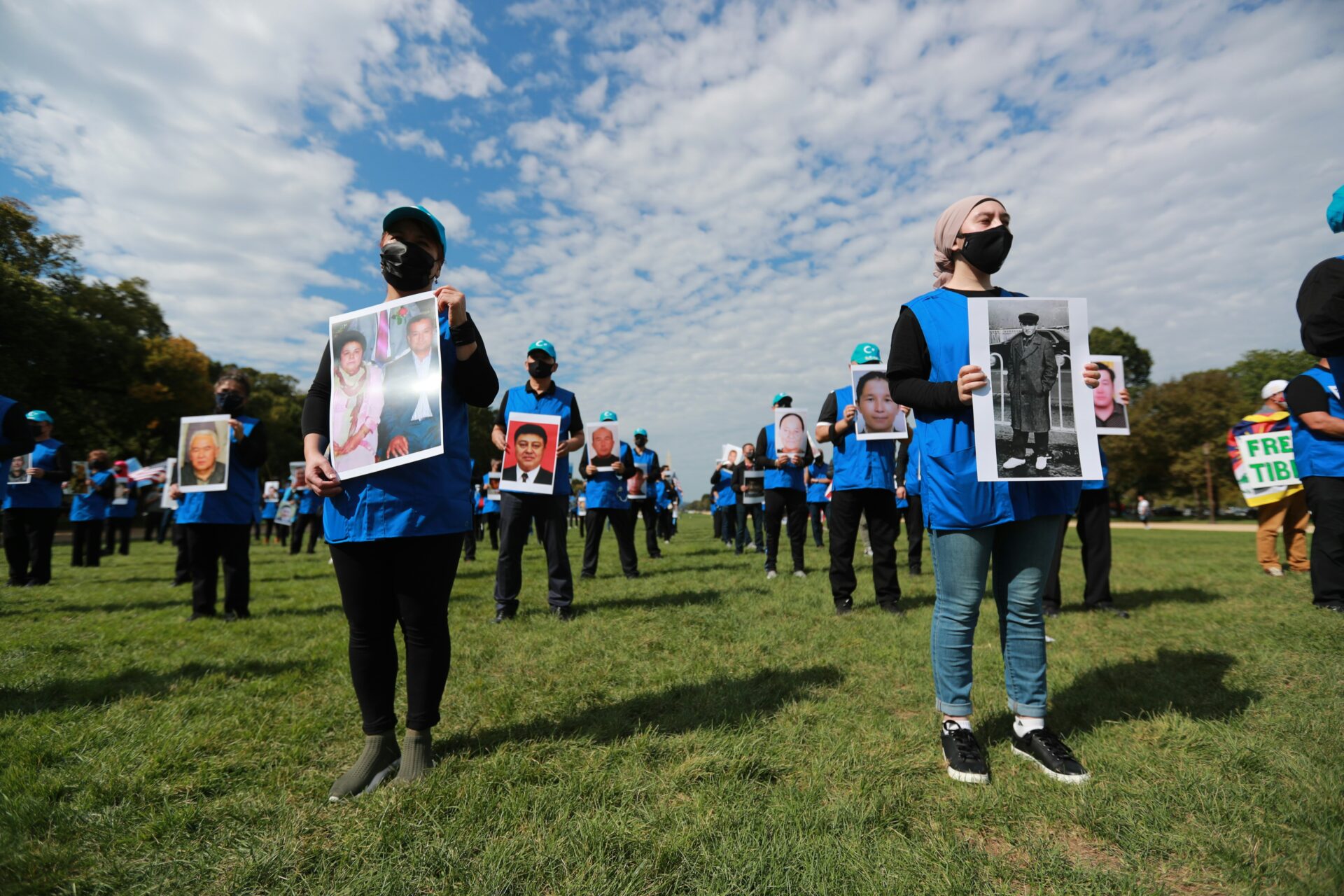 Demonstrators hold photos of Uyghurs detained or disappeared in China, in May 2021 (Kuzzat Altay/Unsplash)