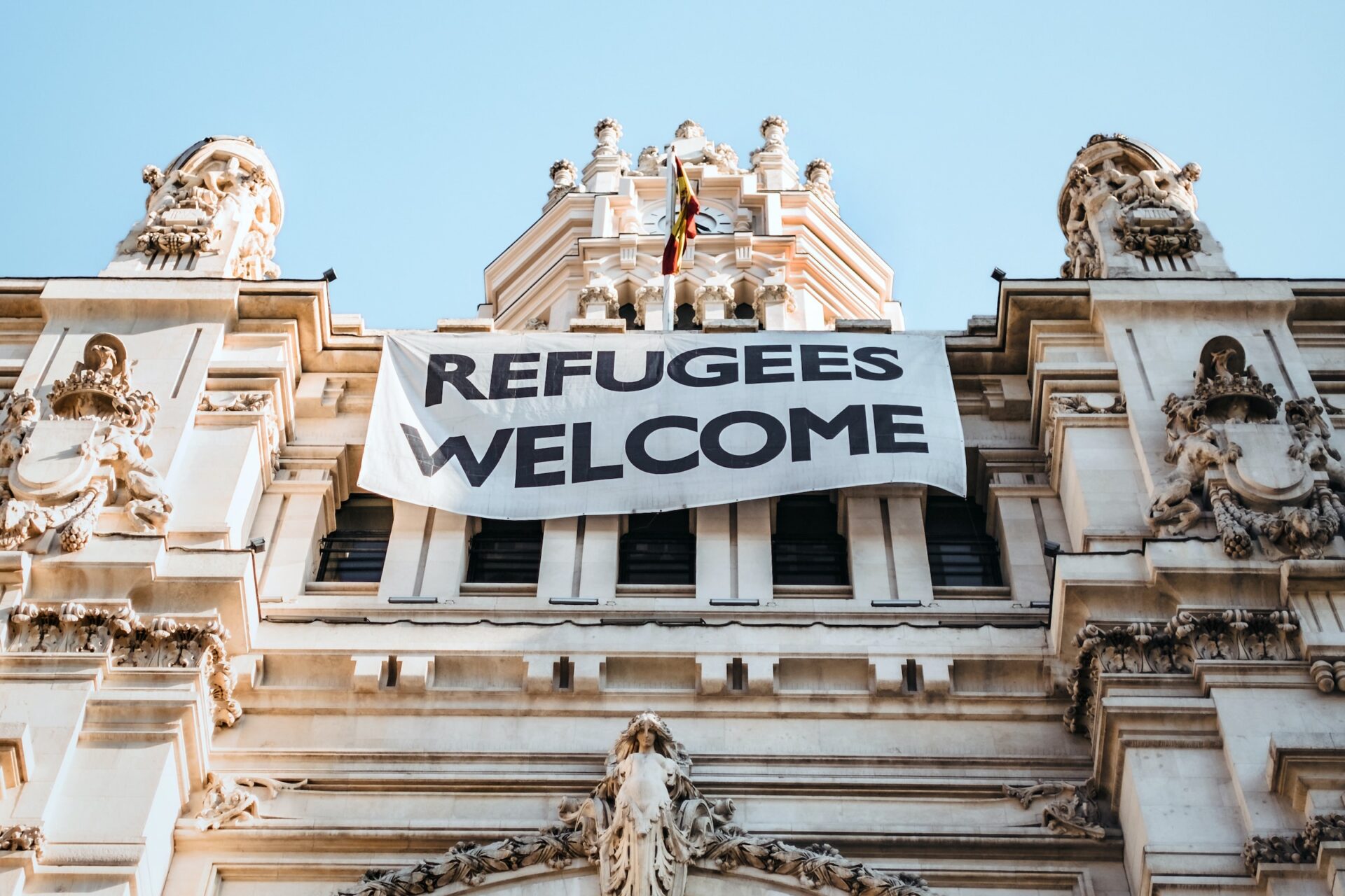 In Madrid, Spain, a building bears a banner that says "refugees welcome" (Maria Teneva/Unsplash)