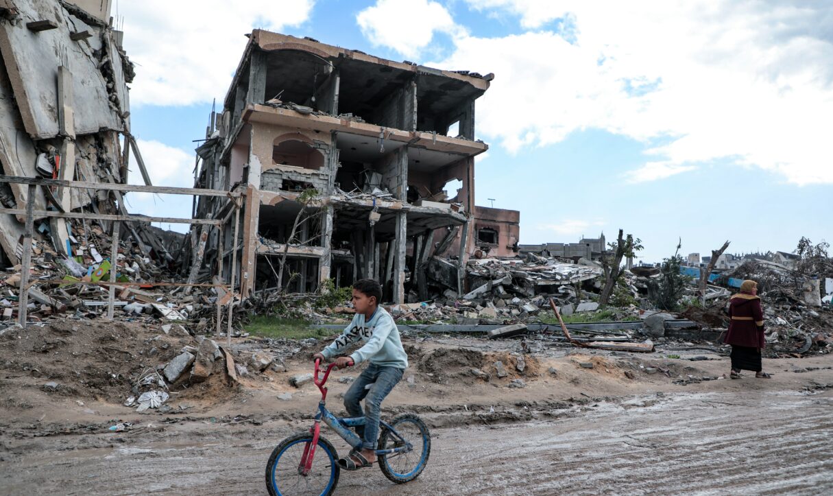 A child rides a bicycle through the destroyed streets of the Gaza Strip's Jabalia refugee camp in June 2025 (Mohammed Ibrahim/Unsplash)
