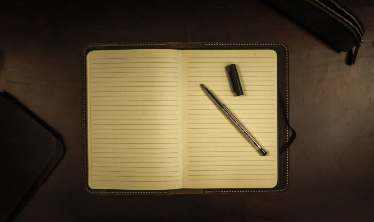 A photograph depicts a pen on an empty notebook on Oct. 24, 2019 (Pedro Araujo/Unsplash)