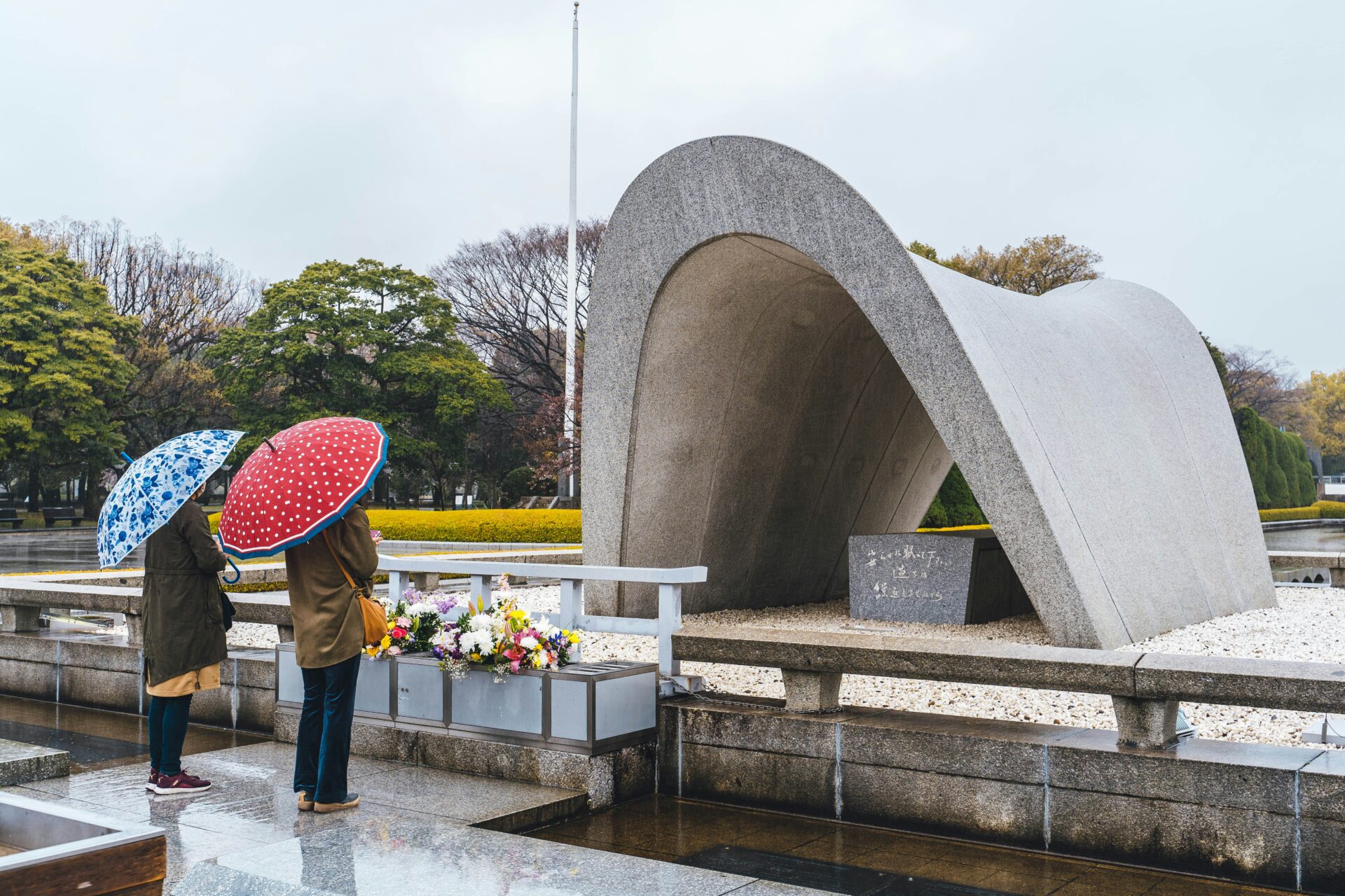 Two people praying in front of the Peace Memorial Park monument in Hiroshima, on March 30, 2022 (Roméo A./Unsplash)