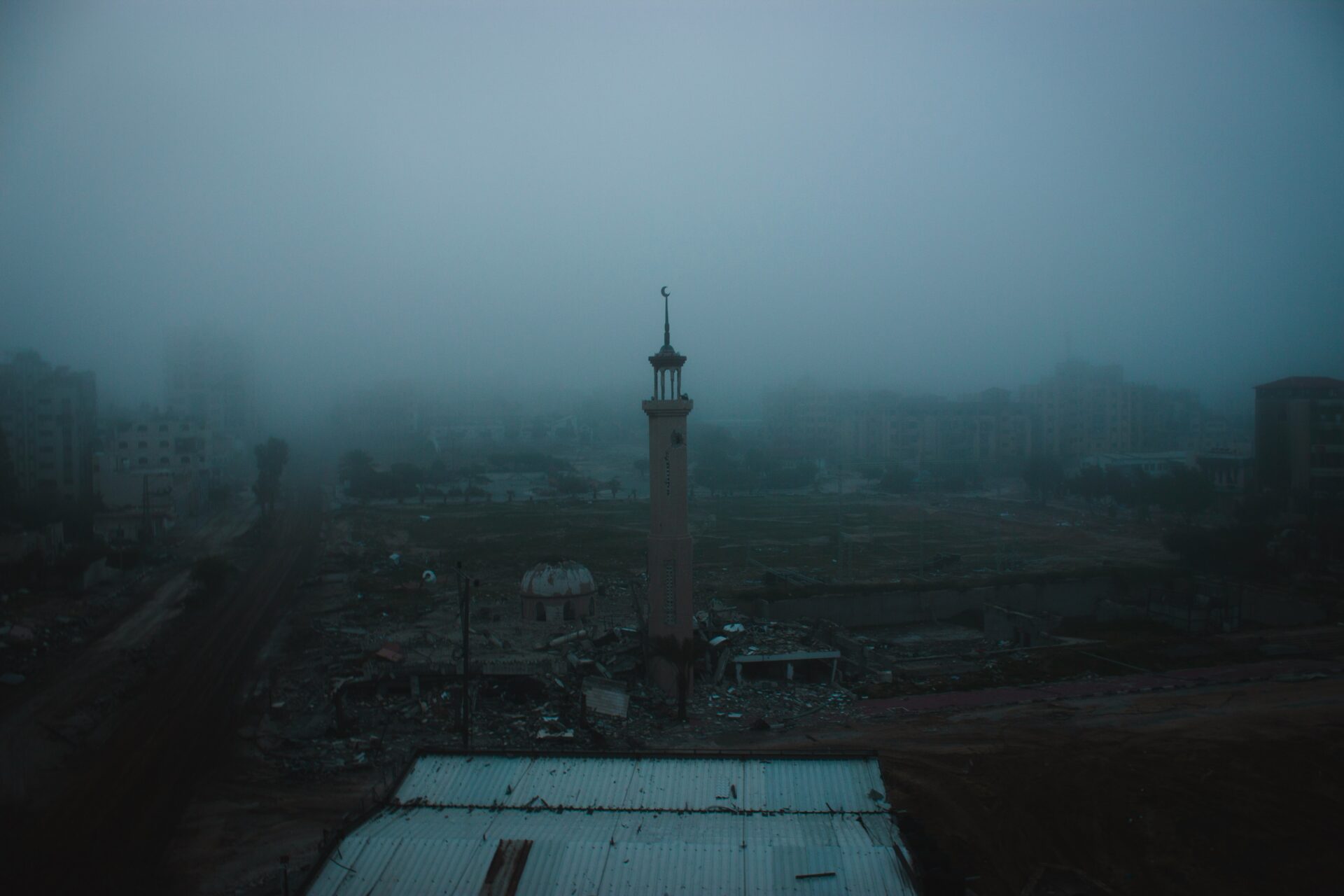 A photo shows a minaret emerging from fog and darkness (Tomer Texler/Unsplash)
